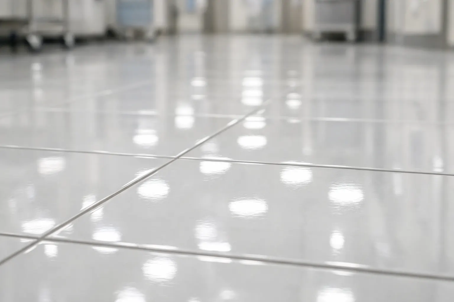 Close-up of a glossy, reflective tiled floor in a bright facility.